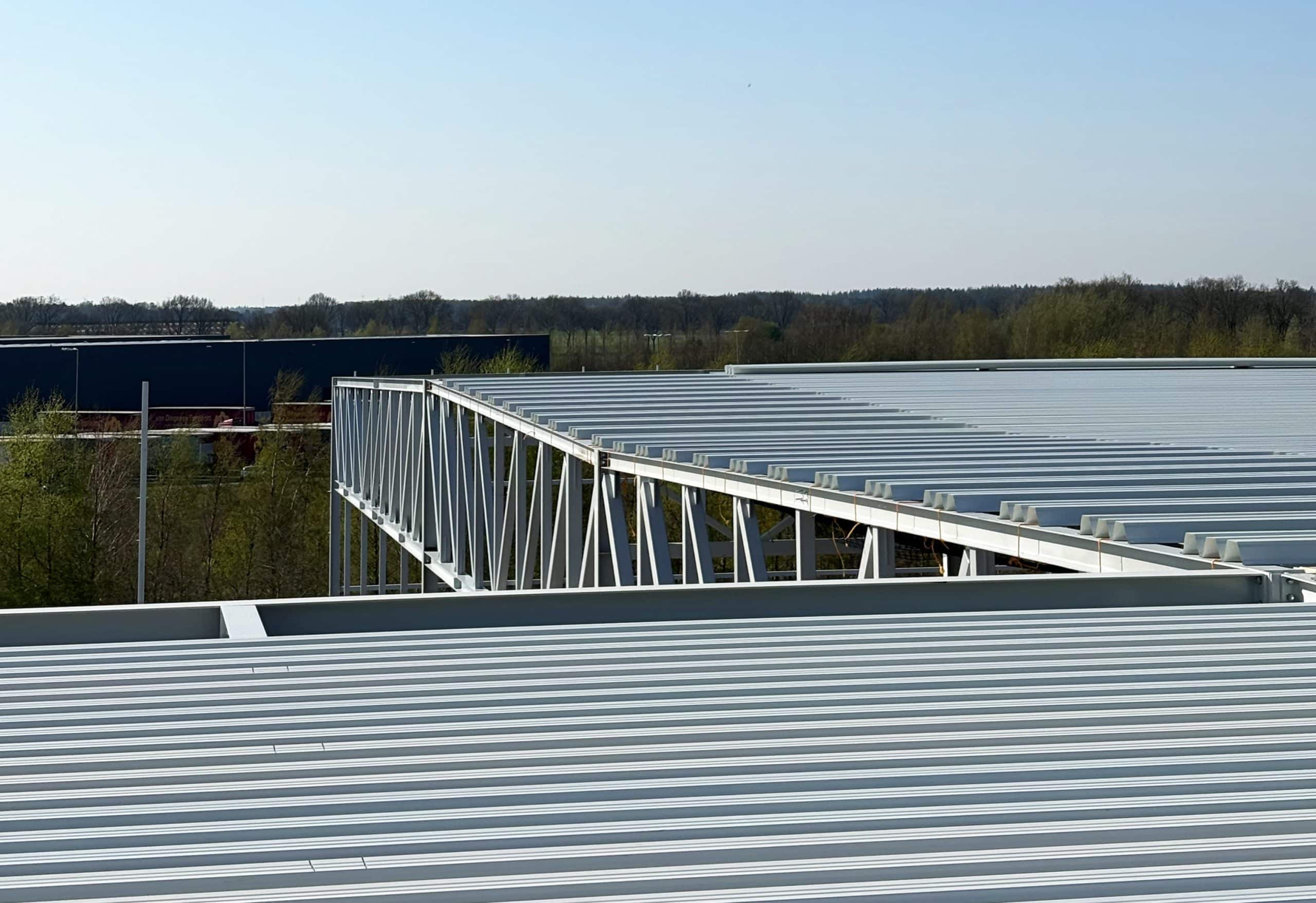 Industriële metalen dakconstructie met bomen op achtergrond.