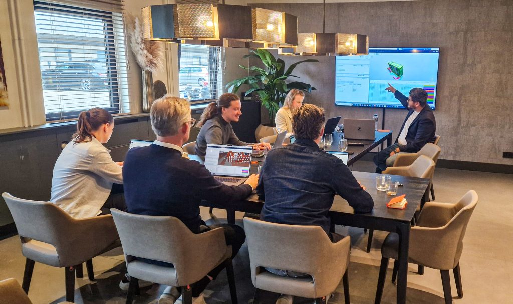 Vergadering met zeven mensen en presentatiescherm
